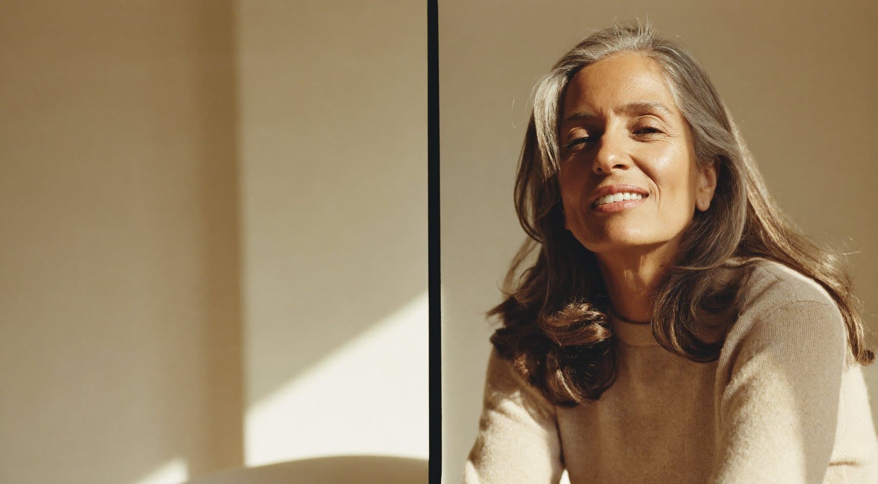 A woman in her fifties smiling warmly in soft natural light