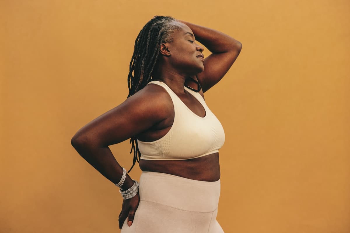 A woman in athletic clothing standing calm and confident in soft light
